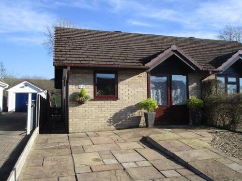 a brick house with a driveway in front of it at Riverside Bungalow - direct river access! in Ystradgynlais