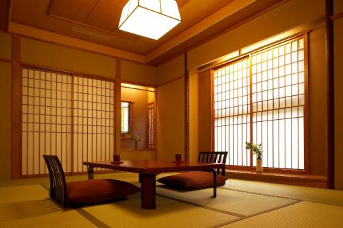 a room with a table and chairs and windows at Futari Shizuka in Komagane