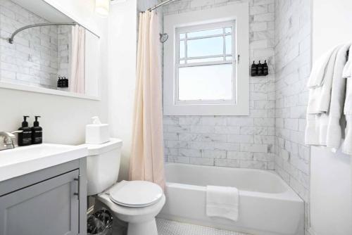 a white bathroom with a tub and a toilet and a sink at Cozy Apartment in Virginia Highland in Atlanta