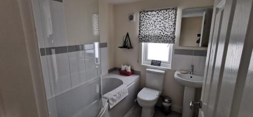 a bathroom with a toilet and a tub and a sink at The Wee Hoose in Dumfries