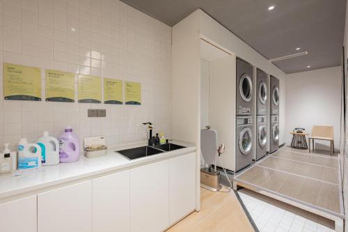 a white kitchen with a sink and washing machines at Atour Hotel Shanghai Jiading Juyuan Wisdom Center in Jiading