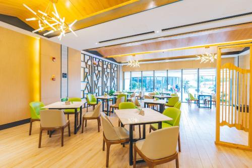 um restaurante com mesas, cadeiras e janelas em Atour Hotel Putuo Zhoushan em Zhoushan