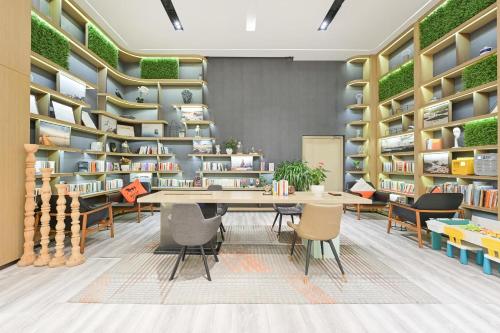 a library with a table and chairs and bookshelves at Atour Hotel Railway Station Dalian in Dalian