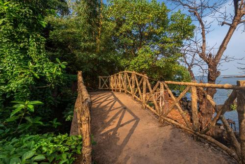 a wooden bridge over a beach with trees and water at SaffronStays Athaang, Dapoli in Ānjarle