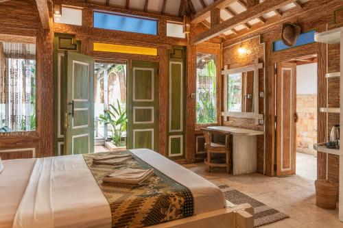 a bedroom with a large bed and a bathroom at Jawa House Private Villas in Gili Trawangan