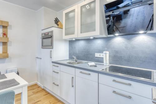 een keuken met witte kasten en een wastafel bij Ferienwohnung AHOI in Norderney