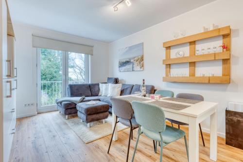een woonkamer met een tafel en stoelen en een bank bij Ferienwohnung AHOI in Norderney