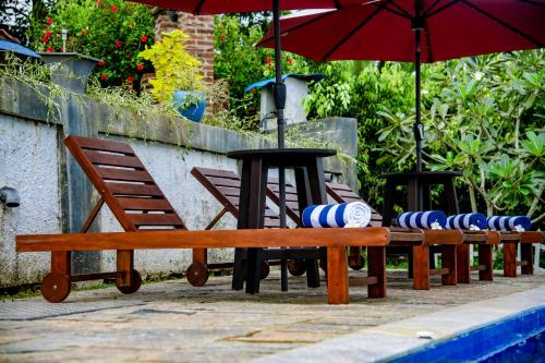 eine Reihe von Holzbänken und einen Tisch mit Sonnenschirmen in der Unterkunft Peaceful Villa with pool near Hikkaduwa in Ambalangoda