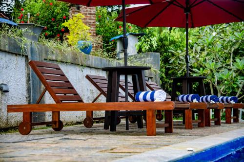 a row of wooden benches and a table with umbrellas at Peaceful Villa with pool near Hikkaduwa in Ambalangoda