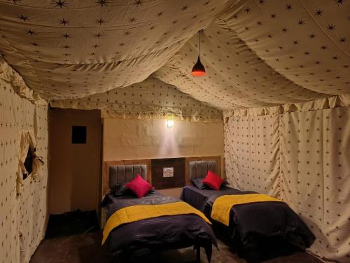 twee bedden in een kamer met een tent bij Riverside Glamping By StayApart x Elephant Brook in Bijni