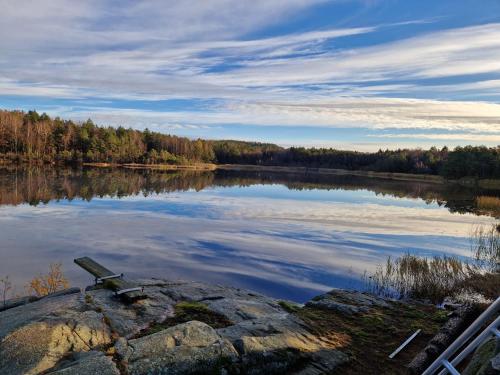 a bench sitting on a rock in front of a lake at The Monastery in Tjøme