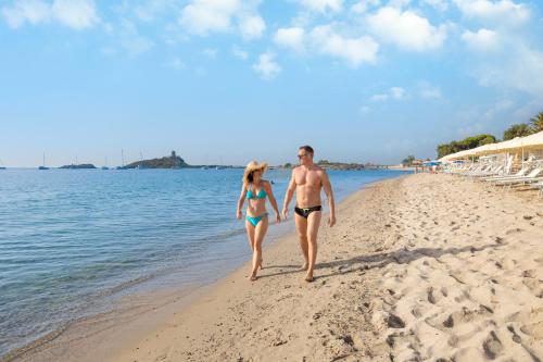 a man and a woman walking on the beach at Hotel Baia Di Nora in Pula