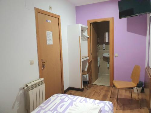 1 dormitorio con paredes de color púrpura, 1 cama y baño en Hostal Abel Victoriano, en Madrid