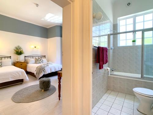 a bedroom with two beds and a shower and a bathroom at Dale Court Guest House in Cape Town