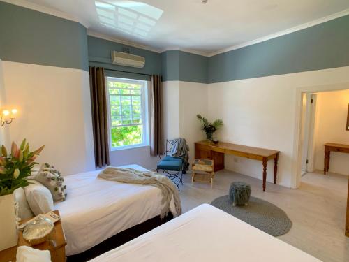 a bedroom with two beds and a desk and a window at Dale Court Guest House in Cape Town
