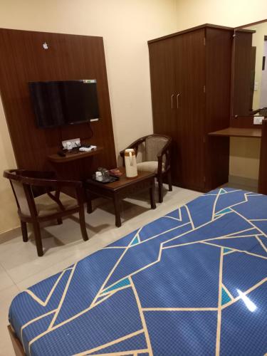 a room with a bed and a table and a tv at ROYAL RESIDENCY in Gangānagar