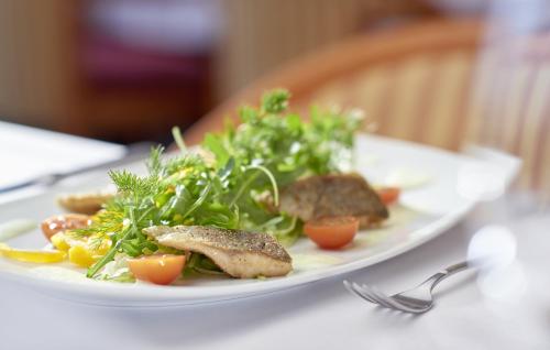 a plate of food with meat and vegetables on a table at Sachsenpark-Hotel in Leipzig