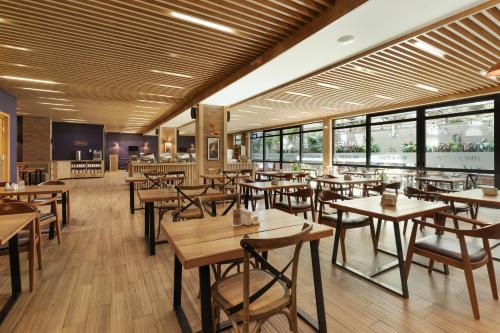 a restaurant with wooden tables and chairs and windows at Iveria Inn Hotel in Tbilisi City