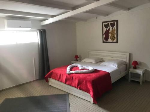 a bedroom with a bed with a red blanket at Les Lauriers du Rocher 2 in Le Diamant