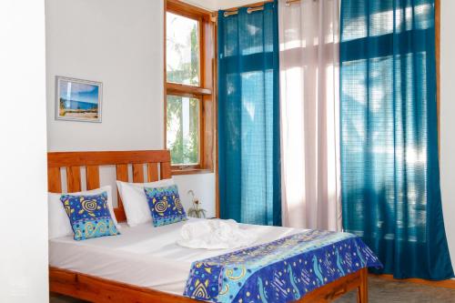 a bedroom with a bed with blue curtains and a window at Canto das Amêijoas in Inhambane