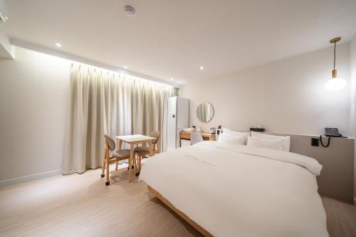 Un dormitorio con una gran cama blanca y una mesa en HOTEL SOHA en Gumi