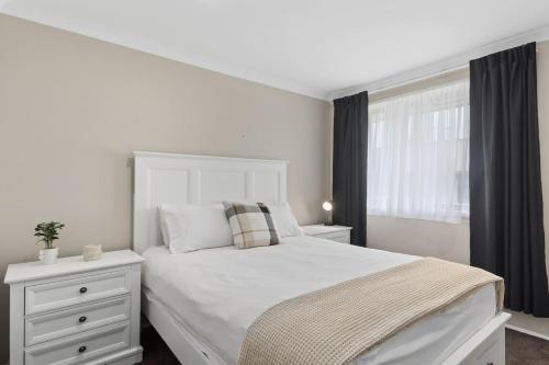 a bedroom with a white bed and a window at 'Pineview Escape' Generous Comfort for Families in Shellharbour