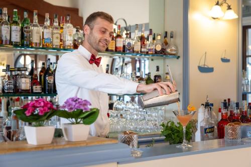 a man pouring a drink at a bar at Hotel Baia Di Nora in Pula
