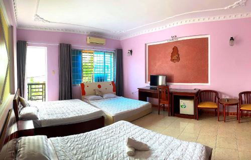 a bedroom with two beds and a desk and a table at OYO 1212 Uyen Phuong Motel in Vung Tau