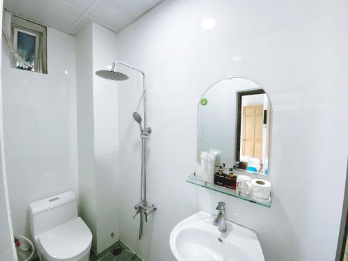 a white bathroom with a sink and a mirror at OYO 1212 Uyen Phuong Motel in Vung Tau