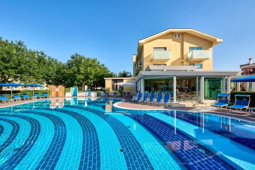 une grande piscine avec des chaises et un bâtiment dans l'établissement Junior Family Hotel, à Cavallino-Treporti