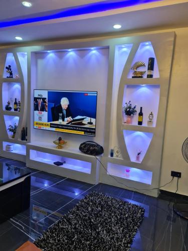 Habitación con TV en una pared con estanterías en Hencap apartment services, en Lagos