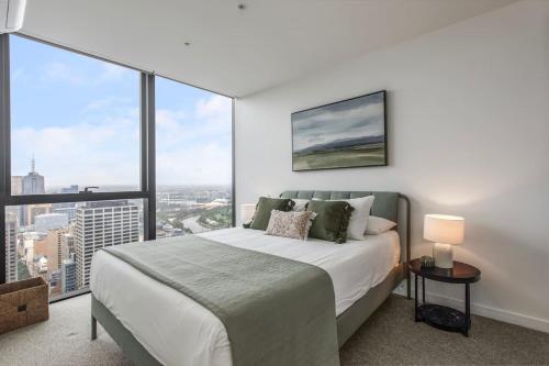 1 dormitorio con 1 cama grande y ventanas grandes en Aloft on Collins - Skyline Views from the 53rd Floor en Melbourne