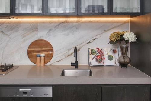 a kitchen counter with a sink and a vase of flowers at Aloft on Collins - Skyline Views from the 53rd Floor in Melbourne