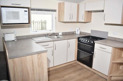 a kitchen with white cabinets and a black stove at Rio Gold LC21 in Minehead