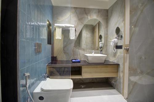 bagno con lavandino, servizi igienici e specchio di Cygnett Collection K K Hotel a Faizābād