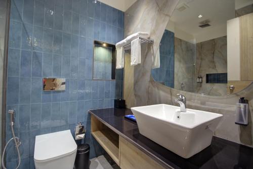 a bathroom with a sink and a toilet and a mirror at Cygnett Collection K K Hotel in Faizābād