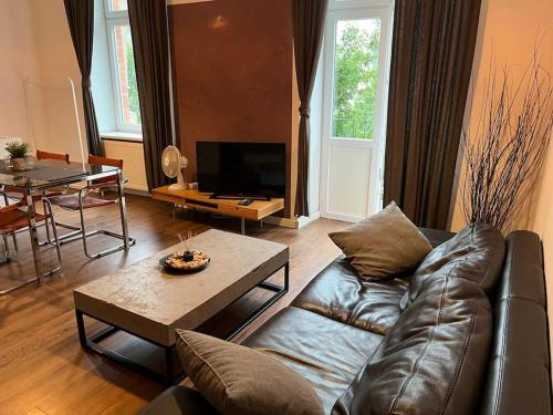 a living room with a leather couch and a table at Venice Loft with balcony downtown in Kraków