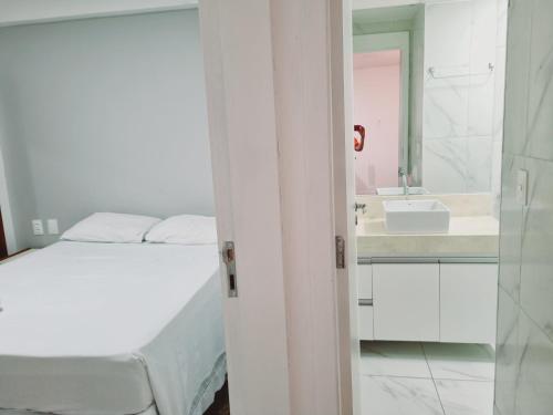 a white bedroom with a bed and a sink at Flats Mar Atlântico Residence in Fortaleza