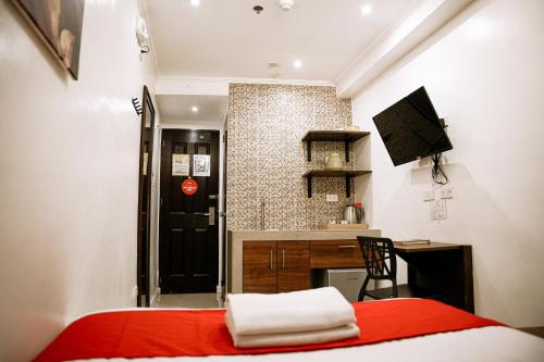 a bedroom with a red bed and a kitchen at Nest Fort BGC in Manila
