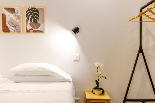 a white bedroom with a bed and a lamp at Ladomar Avenida in Horta