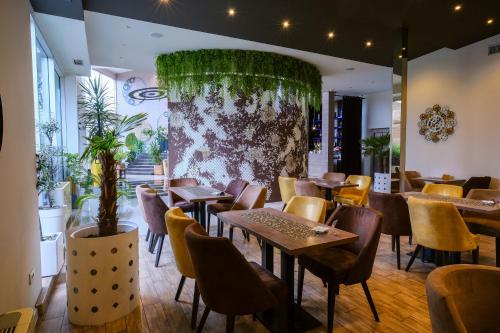 Hotel Crystal Light في نيشْ: مطعم بطاولات وكراسي وجدار بالنباتات