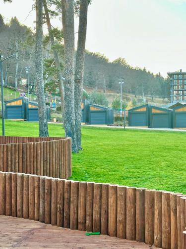 a wooden fence in a park with trees and grass at Villa Mtashi in Bakuriani