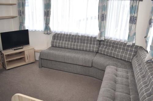 uma sala de estar com um sofá e uma televisão de ecrã plano em Rio Gold LC22 em Minehead