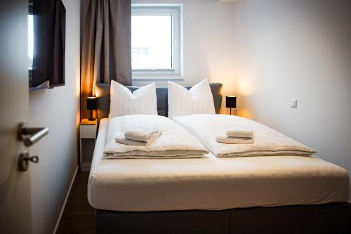 1 dormitorio con 1 cama con sábanas y almohadas blancas en Gebirgsresort - Ferienwohnung Schanzenblick, en Winterberg