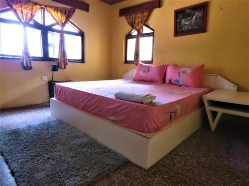 a bedroom with a large bed with pink pillows at Rent your own private beach bungalow in Ampeni