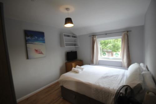 a bedroom with a white bed and a window at Rockingham House Uxbridge in Uxbridge