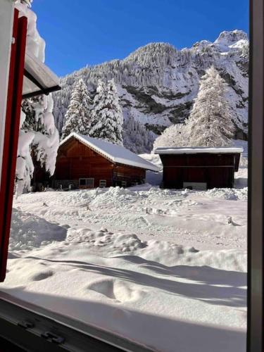 a snow covered cabin in front of a mountain at Mountain View Apartment in Kandersteg