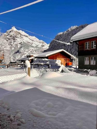 a snow covered building with a mountain in the background at Mountain View Apartment in Kandersteg