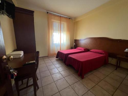 1 dormitorio con 2 camas con sábanas rojas y ventana en Hotel Colosseo Colleferro, en Colleferro