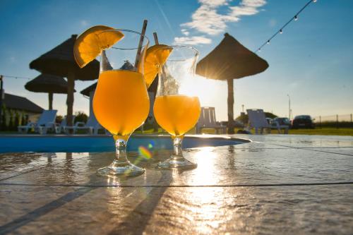 two glasses of orange juice on a table near a pool at Słoneczne Wzgórze Zator in Zator